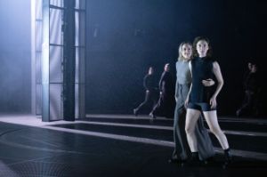 Two performers next to a wall of lights on an otherwise empty stage