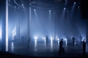 Several performers spread out on a large, mystically lit stage