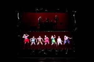 Performers in colourful latex costumes and comical poses