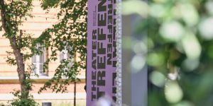 The lettering “Theatertreffen” on a purple background in front of the Haus der Berliner Festspiele.