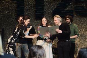 Nora Hertlein-Hull übergibt DARUM die Theatertreffen-Urkunde. Im Hintergrund steht das künstlerische Team.
