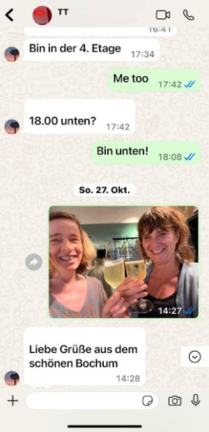 Screenshot of a chat with a photo of Sabine Leucht and Katrin Ullmann toasting with sparkling wine