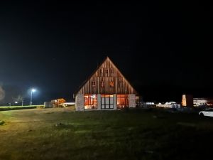 A brightly lit large barn in the middle of a meadow