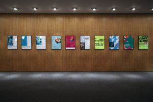 Ten framed posters from the last few years of Tanztreffen der Jugend are hanging on a wood-covered wall.