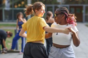 Two young dancers hold each other’s hands in a dance pose facing each other.