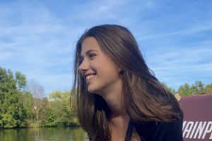 Porträt von Emma Lin, lächelnd im Seitenprofil vor einem Gewässer.