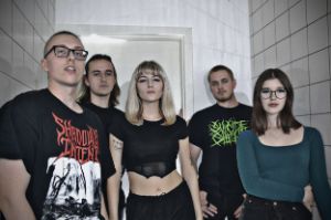 Die fünf Bandmitglieder stehen in dunkler Kleidung und ernster Miene vor weißen Fliesen.