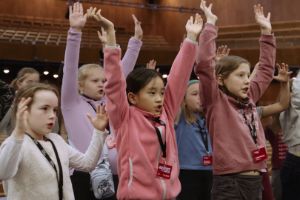 A group of children raise their arms in the air.