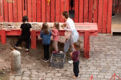 Kinder stehen vor einem mit Sand bedeckten Tisch und wühlen
