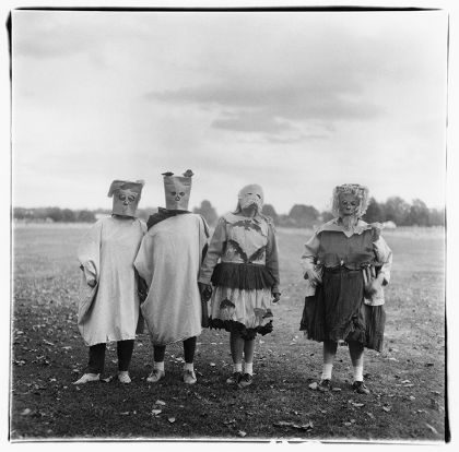 Vier Personen stehen in selbst gemachten Kostümen auf einer Wiese. Die Gesichter der Personen sind durch Masken bedeckt.