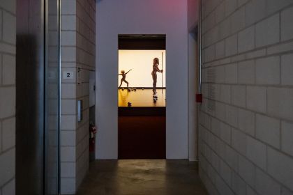 A screen hangs in an empty room, displaying human silhouettes.