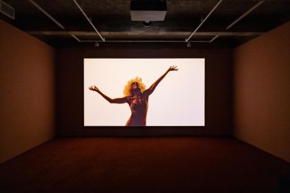 A screen hangs in an empty room, displaying a human silhouette.